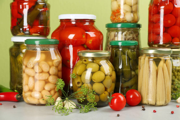 Jars of pickled vegetables and ingredients on light table - Zdjęcie, obraz