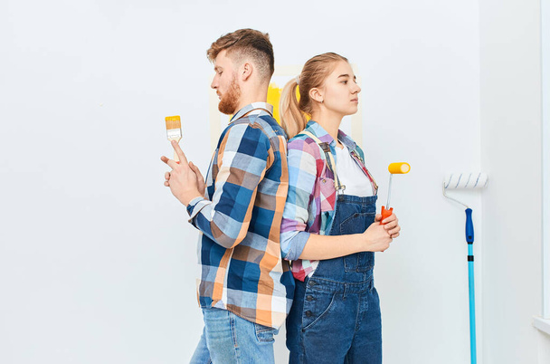 Smiling couple painting at home, holding paint roller and brush isolated - Foto, afbeelding