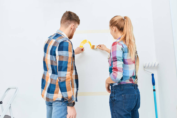 Young happy couple doing DIY repair of their appartment together - Foto, afbeelding