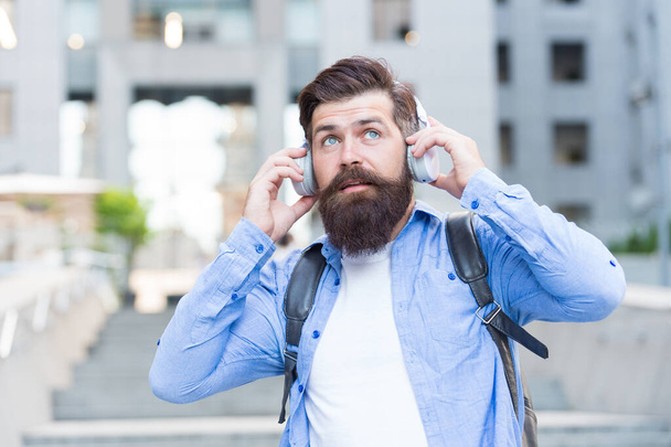 We have our ears in the streets. Bearded man wear ear phones outdoors. Hipster listen to music in headphones. Comfortable ear pads. Hearing protection. Modern life. Ear knowledge for your soul - Foto, imagen