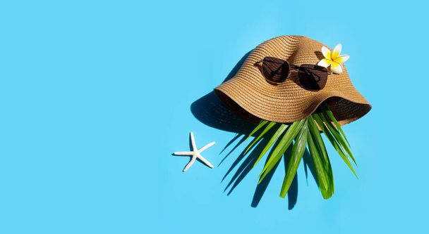 Sombrero de verano con gafas de sol sobre fondo azul. Disfruta del concepto de vacaciones. Copiar espacio - Foto, Imagen