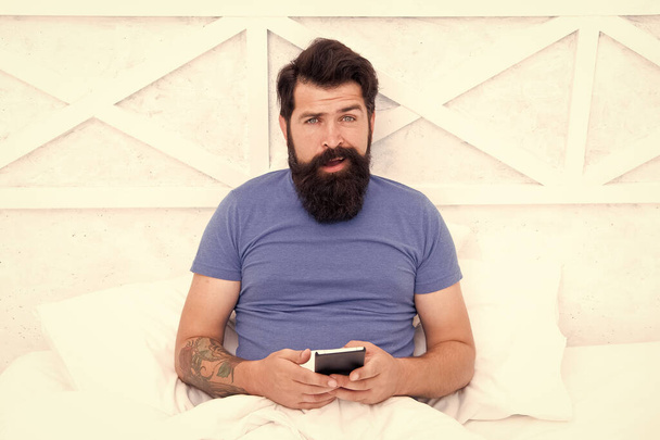 Checking social networks. Cellular communication. Modern guy talking on smartphone in bed. Handsome man with modern mobile phone from home. Modern technology for everyday life. Modern communication - Foto, afbeelding