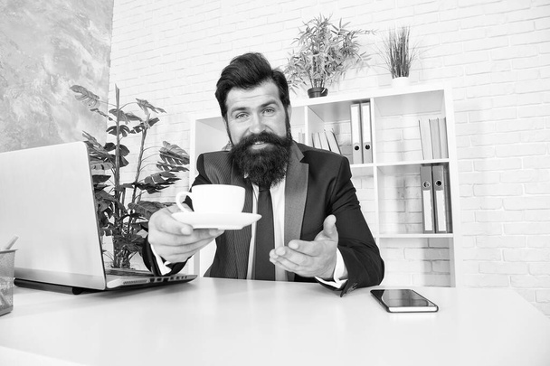 Help yourself please. Happy businessman serve hot cup at desk. Project manager drink tea during work break. Break time. Enjoying break during work day. Productivity soars after coffee break - Фото, зображення