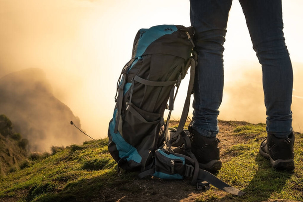 Sisli bir sabahta bir dağın tepesinde sırt çantalı bir adamın bacakları. Seyahat kavramı - Fotoğraf, Görsel