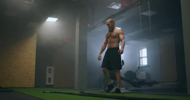 Unavený muž po tréninku s provazy spočívá v tréninkovém sále ve zpomaleném pohybu - Záběry, video