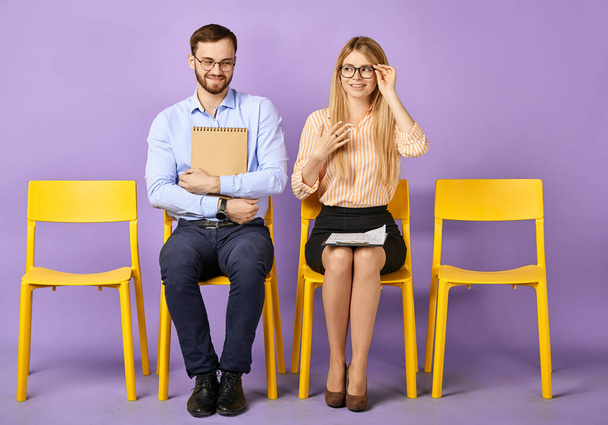 flirting coworkers sitting together on chairs with papers - Photo, Image