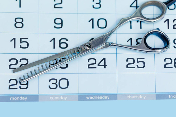 Calendar with hairdressing scissors. Haircut appointment concept. Close-up - Photo, Image