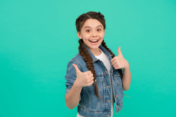 Beauty at its best. Happy child give thumbs up blue background. Little girl smile gesturing thumbs up. Hair salon. Haircare cosmetic products. Approval gesture. Hand sign. She deserves thumbs up - Fotoğraf, Görsel