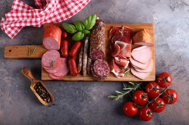 sausage and ham assortment on wooden board - Фото, зображення