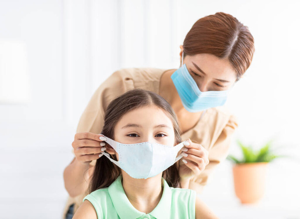 mother help her daughter wearing healthy face mask  - Foto, afbeelding