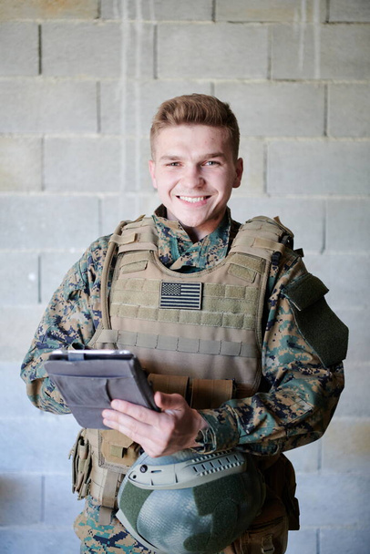 soldier using tablet computer  against old brick wall - Foto, afbeelding