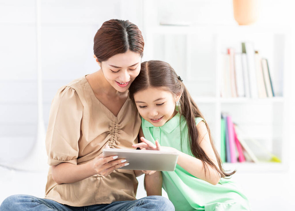 mother and daughter doing homework with  tablet - Foto, Imagen