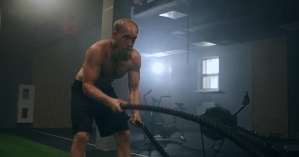 Άνδρας αθλητής γυμνάζεται με σχοινιά σε παλιό κτίριο. Αθλητής σε προπόνηση με σχοινιά κοντά στον καθρέφτη. Σκοινί μάχης - Πλάνα, βίντεο