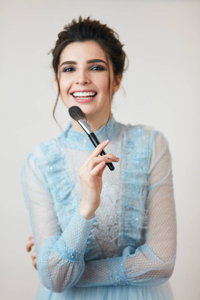 laughing girl with a brush looking at the camera - Фото, изображение