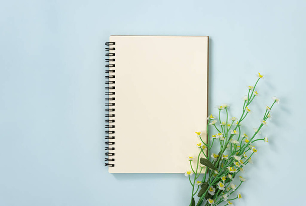 Caderno espiral ou caderno de primavera em tipo não alinhado e flores margaridas brancas na parte inferior direita em fundo minimalista Pastel azul
 - Foto, Imagem