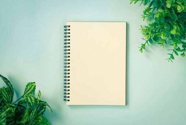 Spiral Notebook or Spring Notebook in Unlined Type and Office Plants at Top Right Corner and Bottom Left Corner on Blue Pastel Minimalist Background in Vintage Tone - Fotoğraf, Görsel