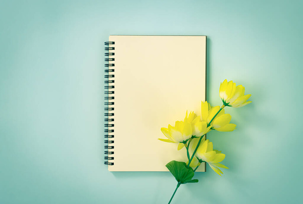 Spirale Notizbuch oder Frühling Notizbuch in ungefütterter Schrift und gelbe Blumen unten rechts auf blauem Pastell minimalistischen Hintergrund in Vintage-Ton - Foto, Bild