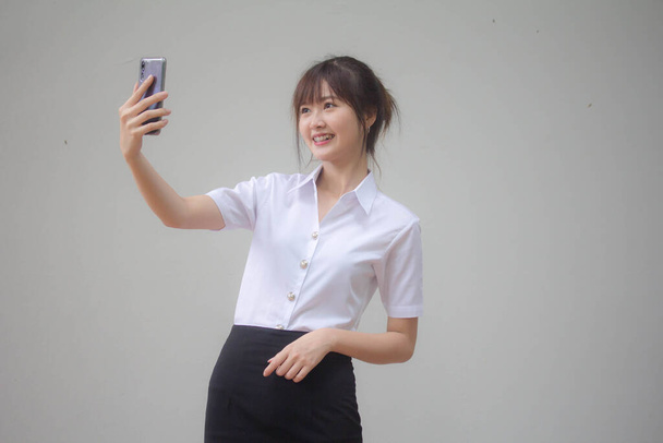 Πορτρέτο του Thai ενηλίκων φοιτητής πανεπιστήμιο ομοιόμορφη όμορφη κοπέλα χρησιμοποιώντας έξυπνο τηλέφωνό της Selfie - Φωτογραφία, εικόνα