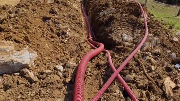 CLOSE UP: Red utility conduits run along the deep trench near construction site - Footage, Video
