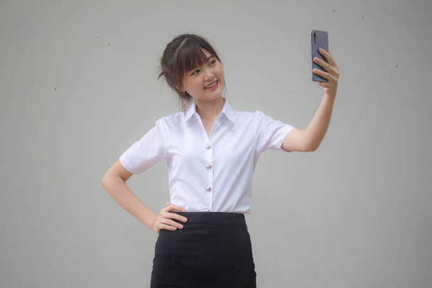 Portrait de thai adulte étudiant uniforme universitaire belle fille en utilisant son téléphone intelligent Selfie - Photo, image