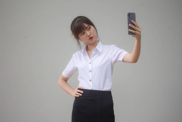 Πορτρέτο του Thai ενηλίκων φοιτητής πανεπιστήμιο ομοιόμορφη όμορφη κοπέλα χρησιμοποιώντας έξυπνο τηλέφωνό της Selfie - Φωτογραφία, εικόνα