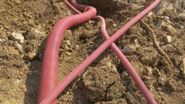 CLOSE UP: Corrugated tubing lies inside a trench near a road under construction. - Footage, Video