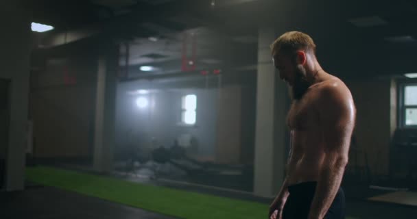 Tired male athlete in the gym rests and prepares to perform an exercise. Slow-motion sweaty athlete breathes heavily and concentrates on exercise - Video