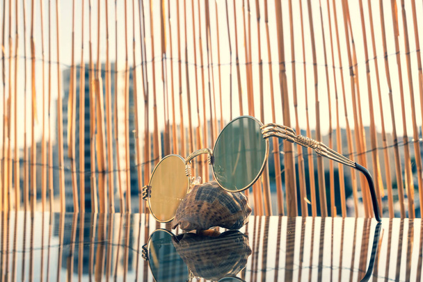 Modelo de gafas de sol vintage con lente redonda disparar fuera con bacdground de bambú. Enfoque selectivo  - Foto, imagen