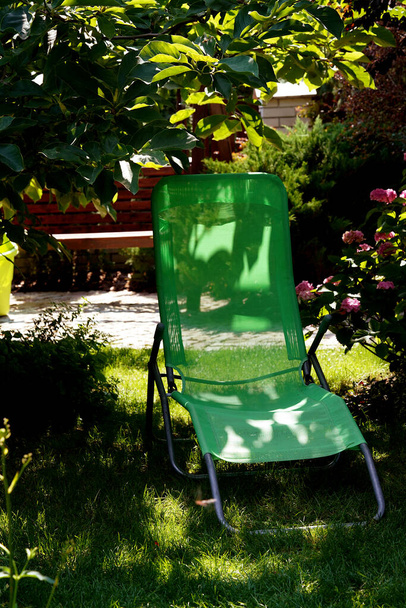 lege ligstoel op een zonnige dag in de schaduw onder een tuinboom - Foto, afbeelding