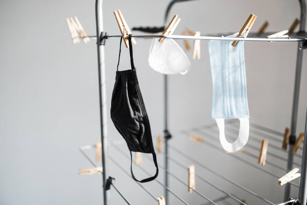 the new normal after the covid-19 virus outbreak and pandemic, different types of face masks hung to dry on clothes airer - Foto, imagen