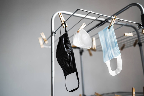 the new normal after the covid-19 virus outbreak and pandemic, different types of face masks hung to dry on clothes airer - Foto, Bild