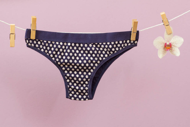 New black women panties on clothesline with clothespins and orchid flower in lilac background. Woman underwear. - Photo, Image
