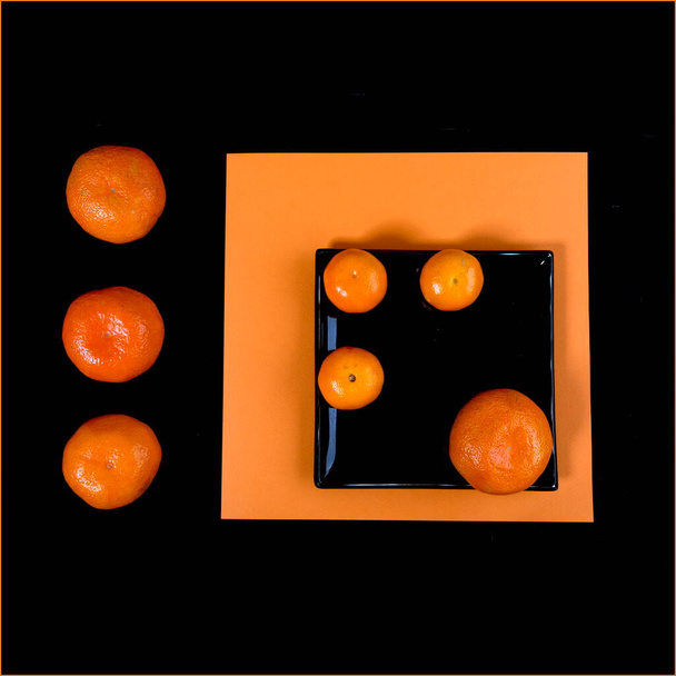 Composição de tangerina laranja e placa quadrada preta em uma mesa laranja. Deitado. Mandarim Malevich. Vista de cima
. - Foto, Imagem