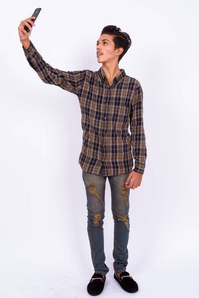 Studio shot of young handsome Indian hipster teenage boy against white background - Foto, Bild
