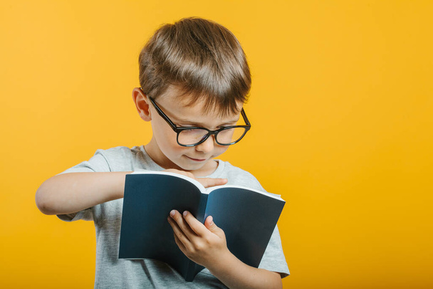 child reads a book against a bright wall - Zdjęcie, obraz