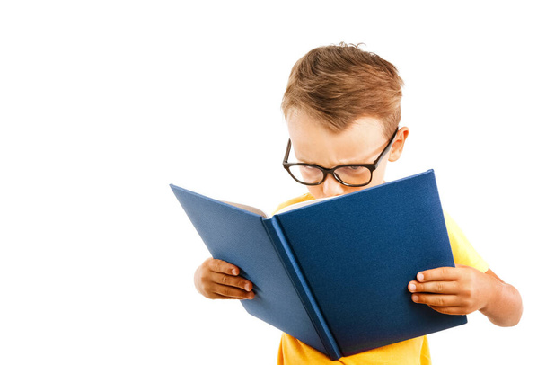 child reads a book against a bright wall - Φωτογραφία, εικόνα