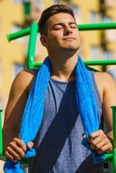 Handsome guy relaxing after outdoor workout. Fit happy man feeling healthy enjoying sun - Φωτογραφία, εικόνα
