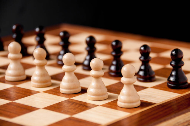 Still life on the chessboard: white and black pawns stand in a row - Foto, afbeelding