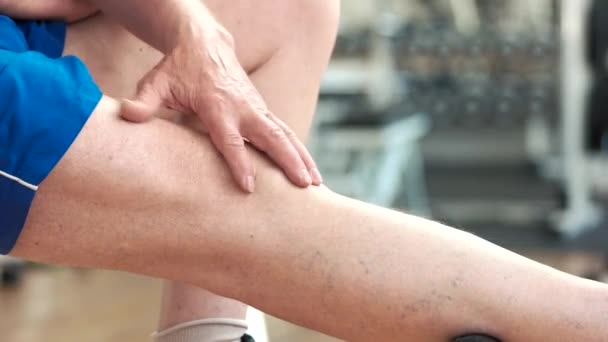 starší muž masíruje koleno v tělocvičně - Záběry, video