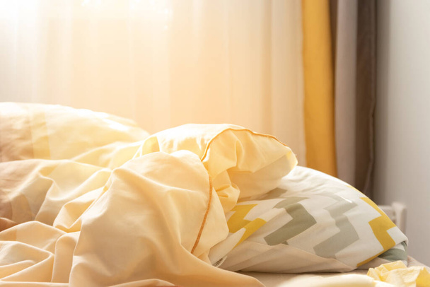Gestreiftes Kissen und Bettdecke auf dem Bett in der Morgensonne in der Wohnung - Foto, Bild