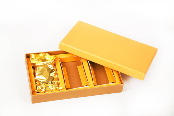 close-up view of brown box with golden wrapping paper isolated on white background - 写真・画像