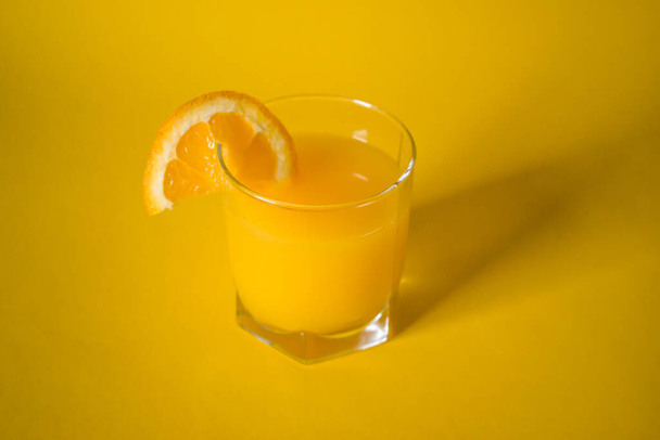 Fresh orange juice with slice of orange on yellow background - Foto, Imagem