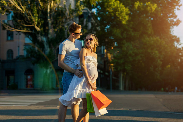 Retrato de pessoas felizes marido e mulher grávida fazendo compras e se divertindo na rua da cidade
 - Foto, Imagem