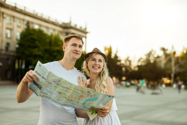 vacaciones de verano, citas y concepto de turismo - pareja sonriente en gafas de sol con mapa en la ciudad - Foto, Imagen