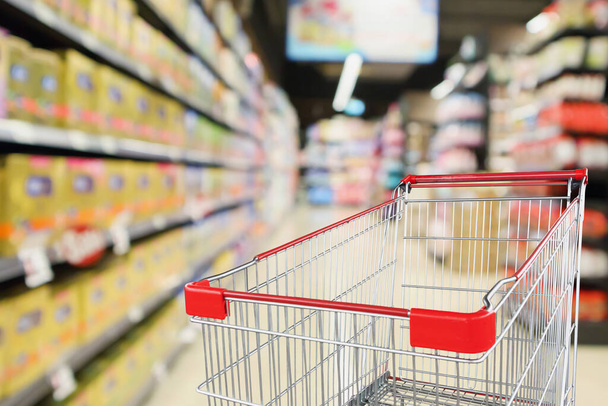 Empty shopping cart with abstract blur supermarket discount store aisle and baby milk product shelves interior defocused background - Photo, Image