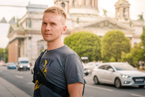 Nuori vaalea mies, jolla on reppu kävelee kadulla Pyhän Isaacin katedraalin vieressä Pietarissa - Valokuva, kuva