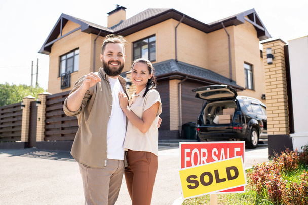 Portrait of excited young couple have bought house and showing key to camera, moving into new house concept - Photo, image