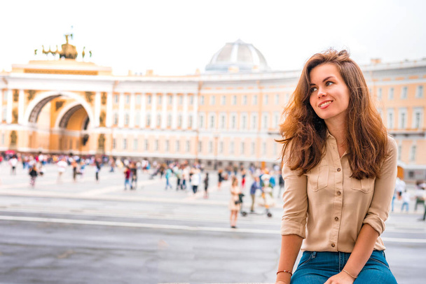 Een mooie vrouw met lang haar bezoekt de toeristische stad Sint-Petersburg tijdens een verblijf in de belangrijkste attractie op het Paleis plein in het centrum - Foto, afbeelding