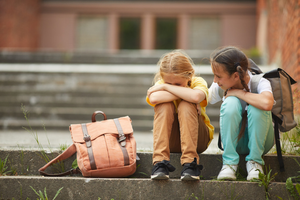 Retrato de comprimento total de adolescente colegial chorando enquanto sentado em escadas ao ar livre com amigo sorridente confortando-a, espaço de cópia - Foto, Imagem