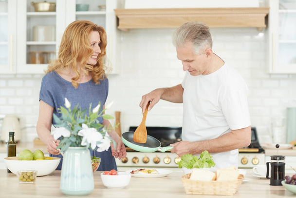 Περιμένετε το πορτρέτο του χαρούμενου ώριμου ζευγαριού απολαμβάνοντας το μαγείρεμα μαζί στο σπίτι σε λευκό εσωτερικό κουζίνα, αντιγραφή χώρου - Φωτογραφία, εικόνα